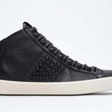 Side profile of mid top black sneaker. Full leather upper with studs, an internal zip and vintage rubber sole.