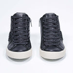Front view of mid top black sneaker. Full leather upper with studs, an internal zip and vintage rubber sole.