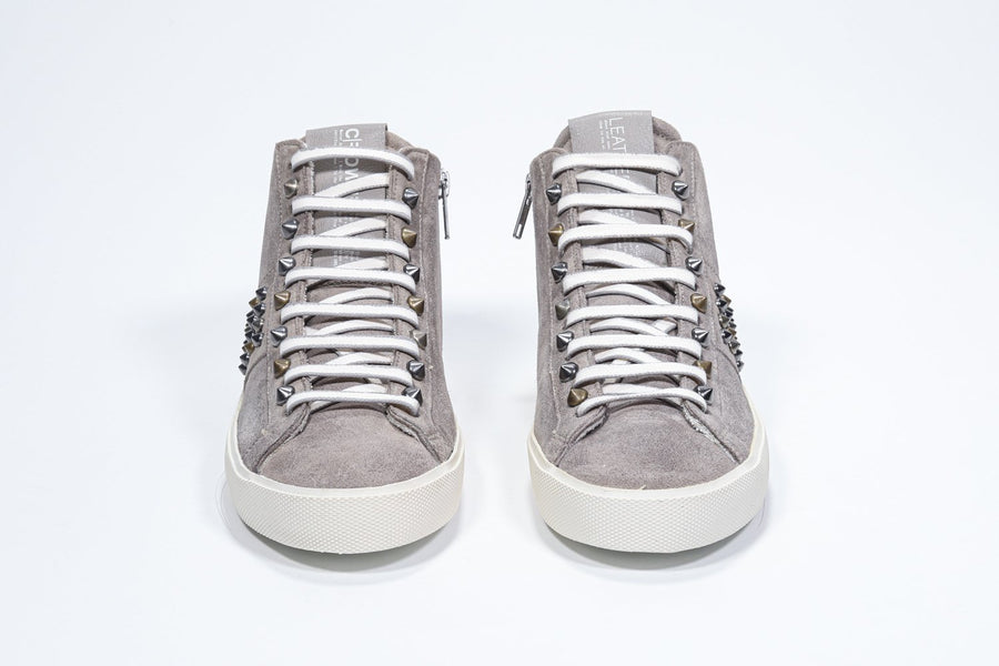 Front view of mid top beige sneaker. Full suede upper with studs, an internal zip and vintage rubber sole.