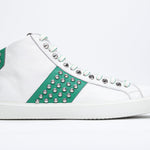 Side profile of mid top white and green sneaker. Full leather upper with studs, an internal zip and white rubber sole.