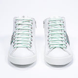 Front view of mid top white and green sneaker. Full leather upper with studs, an internal zip and white rubber sole.