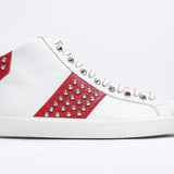 Side profile of mid top white and red sneaker. Full leather upper with studs, an internal zip and white rubber sole.