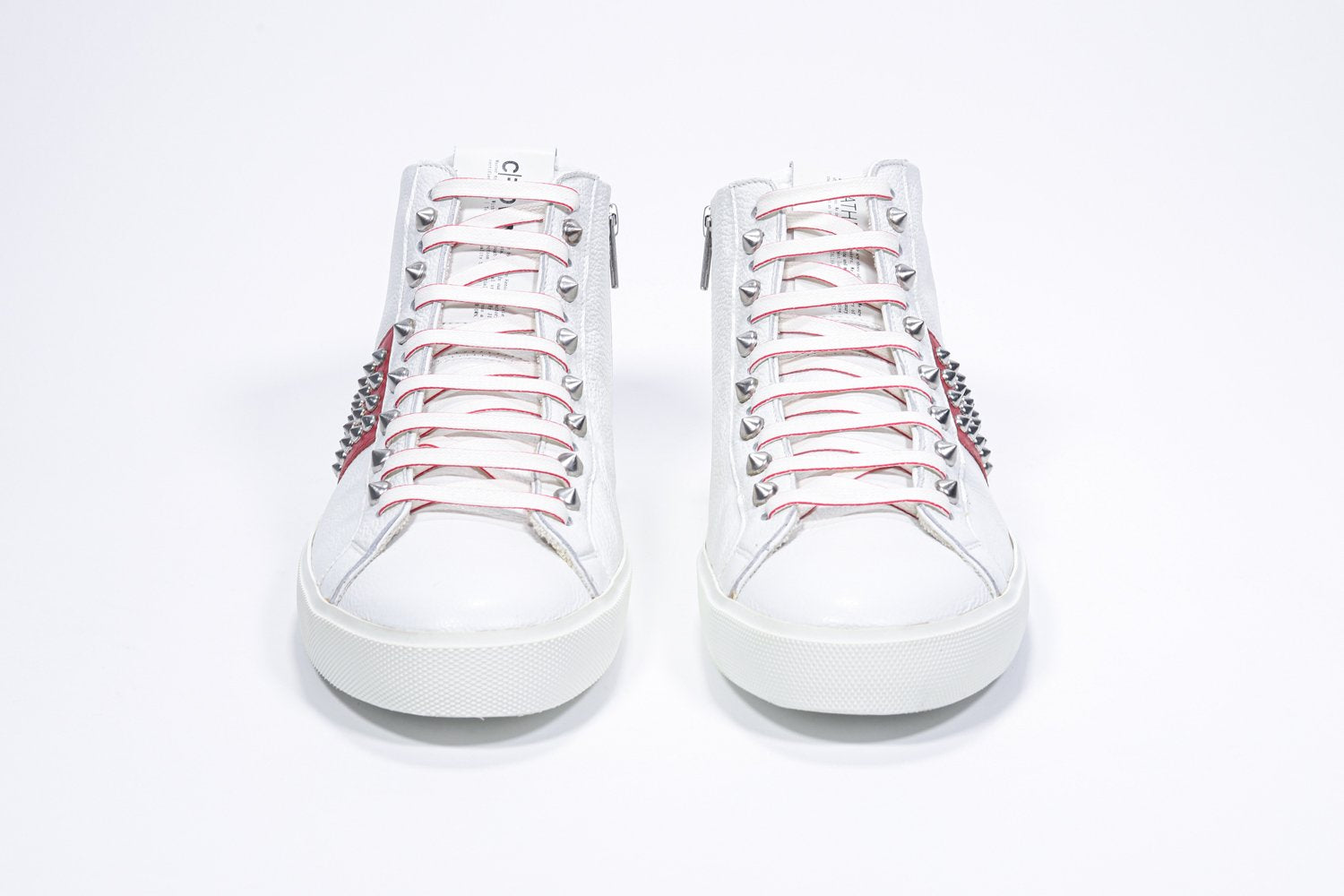 Vue de face du modèle mid top blanc et rouge sneaker. Tige en cuir avec clous, fermeture à glissière intérieure et semelle en caoutchouc blanc.