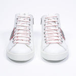 Front view of mid top white and red sneaker. Full leather upper with studs, an internal zip and white rubber sole.