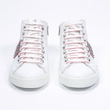 Vue de face du modèle mid top blanc et rouge sneaker. Tige en cuir avec clous, fermeture à glissière intérieure et semelle en caoutchouc blanc.