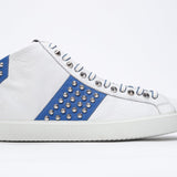 Profilo laterale di mid top bianco e blu royal sneaker. Tomaia in pelle con borchie, zip interna e suola in gomma bianca.