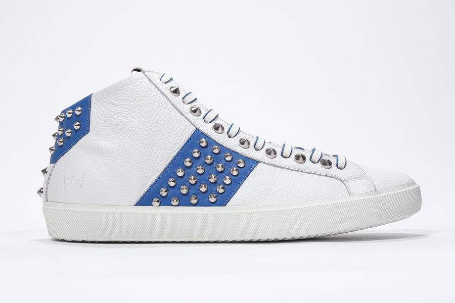 Side profile of mid top white and royal blue sneaker. Full leather upper with studs, an internal zip and white rubber sole.