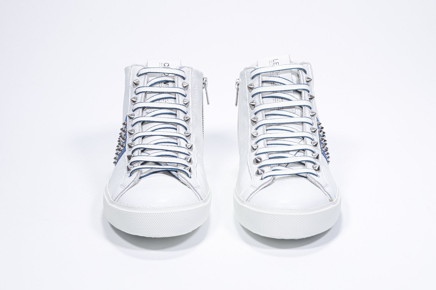 Vista frontale della mid top bianca e blu reale sneaker. Tomaia in pelle con borchie, zip interna e suola in gomma bianca.