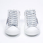 Front view of mid top white and royal blue sneaker. Full leather upper with studs, an internal zip and white rubber sole.