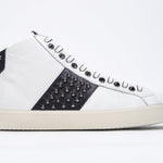 Profilo laterale di mid top bianco e navy sneaker. Tomaia in pelle con borchie, zip interna e suola in gomma vintage.