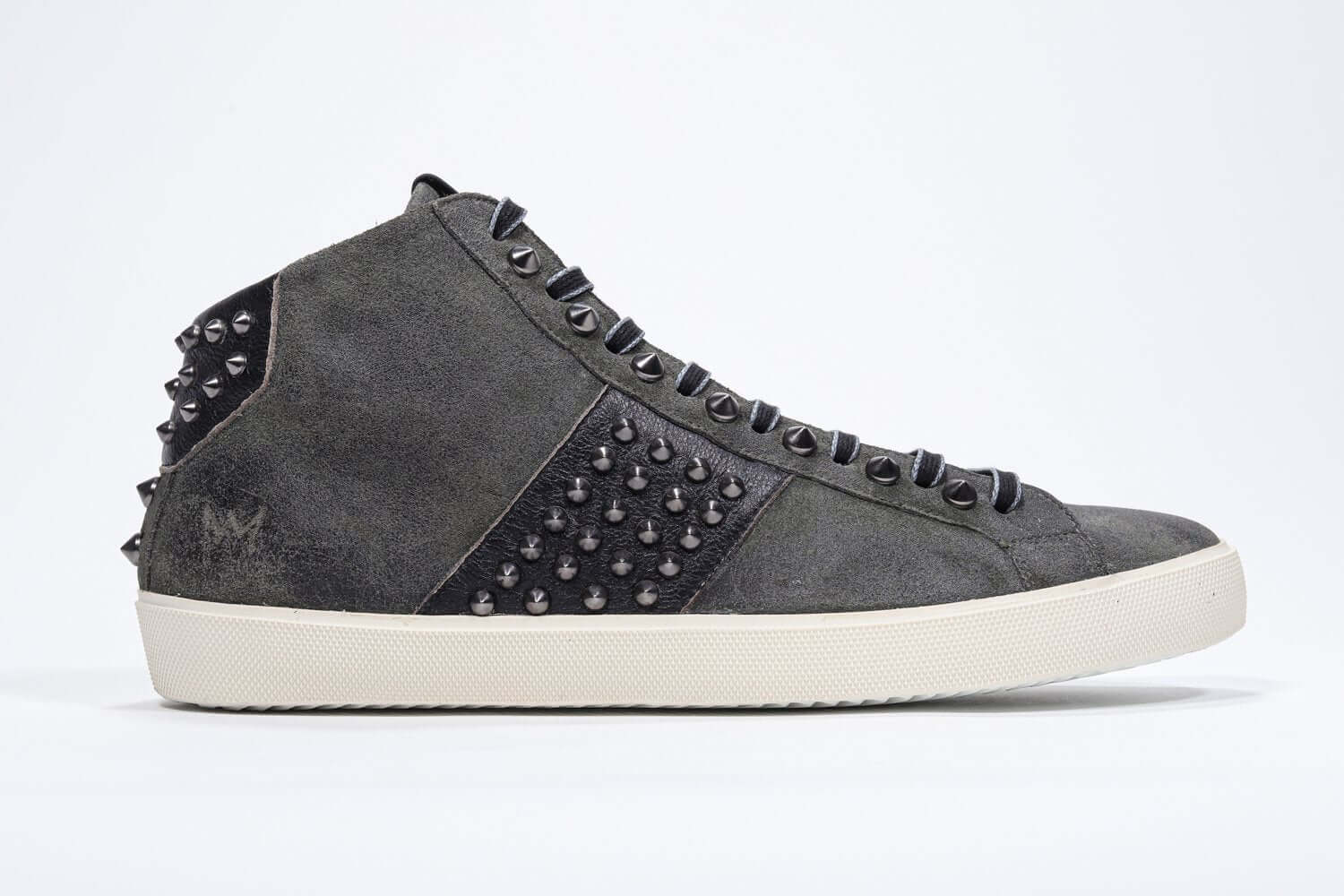 Side profile of mid top military green sneaker. Suede and leather upper with studs, an internal zip and vintage rubber sole.
