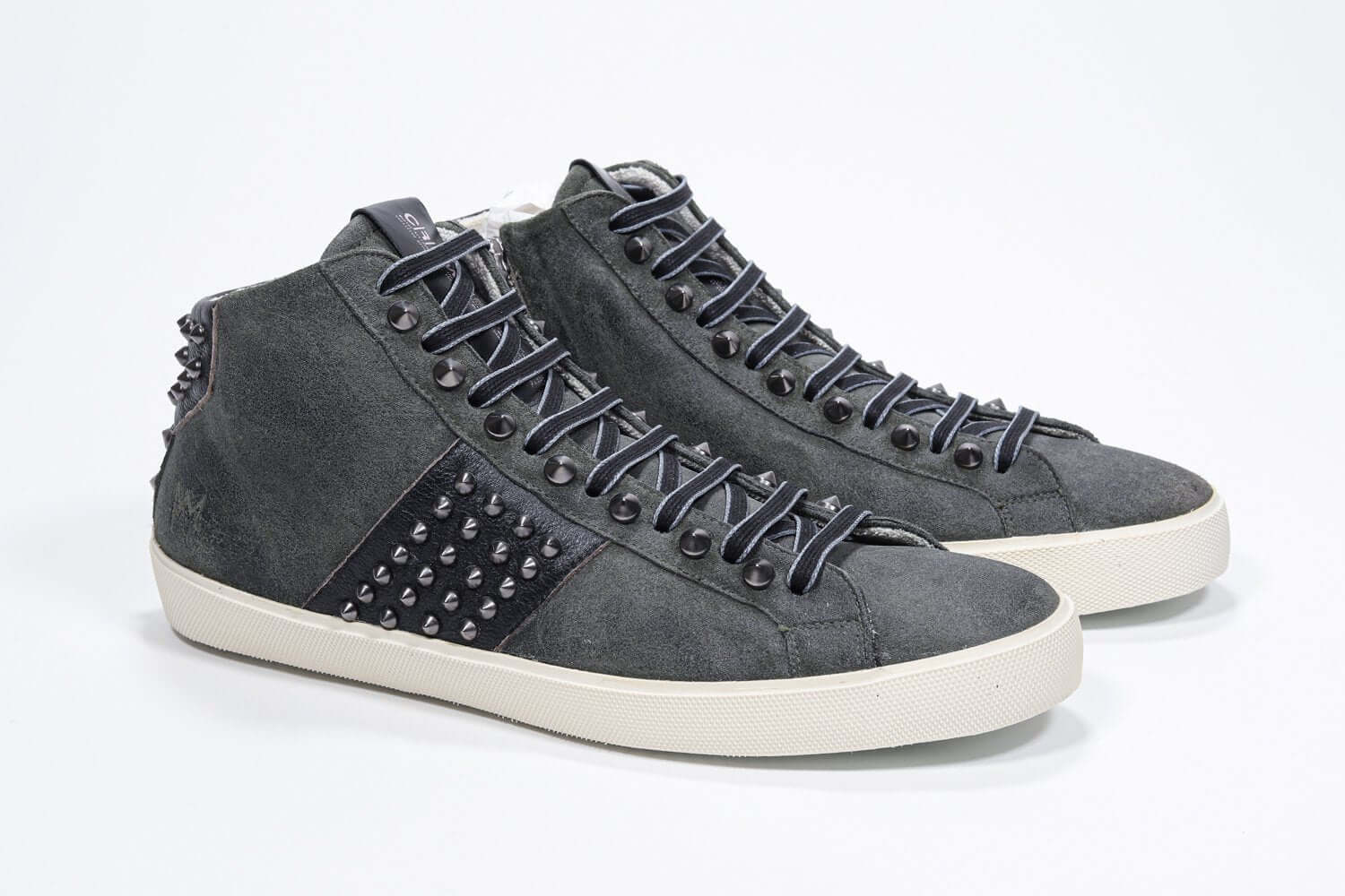 Three quarter front view of mid top military green sneaker. Suede and leather upper with studs, an internal zip and vintage rubber sole.