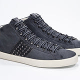 Three quarter front view of mid top navy sneaker. Suede and leather upper with studs, an internal zip and vintage rubber sole.