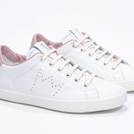 Three quarter front view of low top white sneaker with pale pink detailing and perforated crown logo on upper. Full leather upper and white rubber sole.