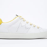 Side profile of low top white sneaker with yellow detailing and perforated crown logo on upper. Full leather upper and white rubber sole.
