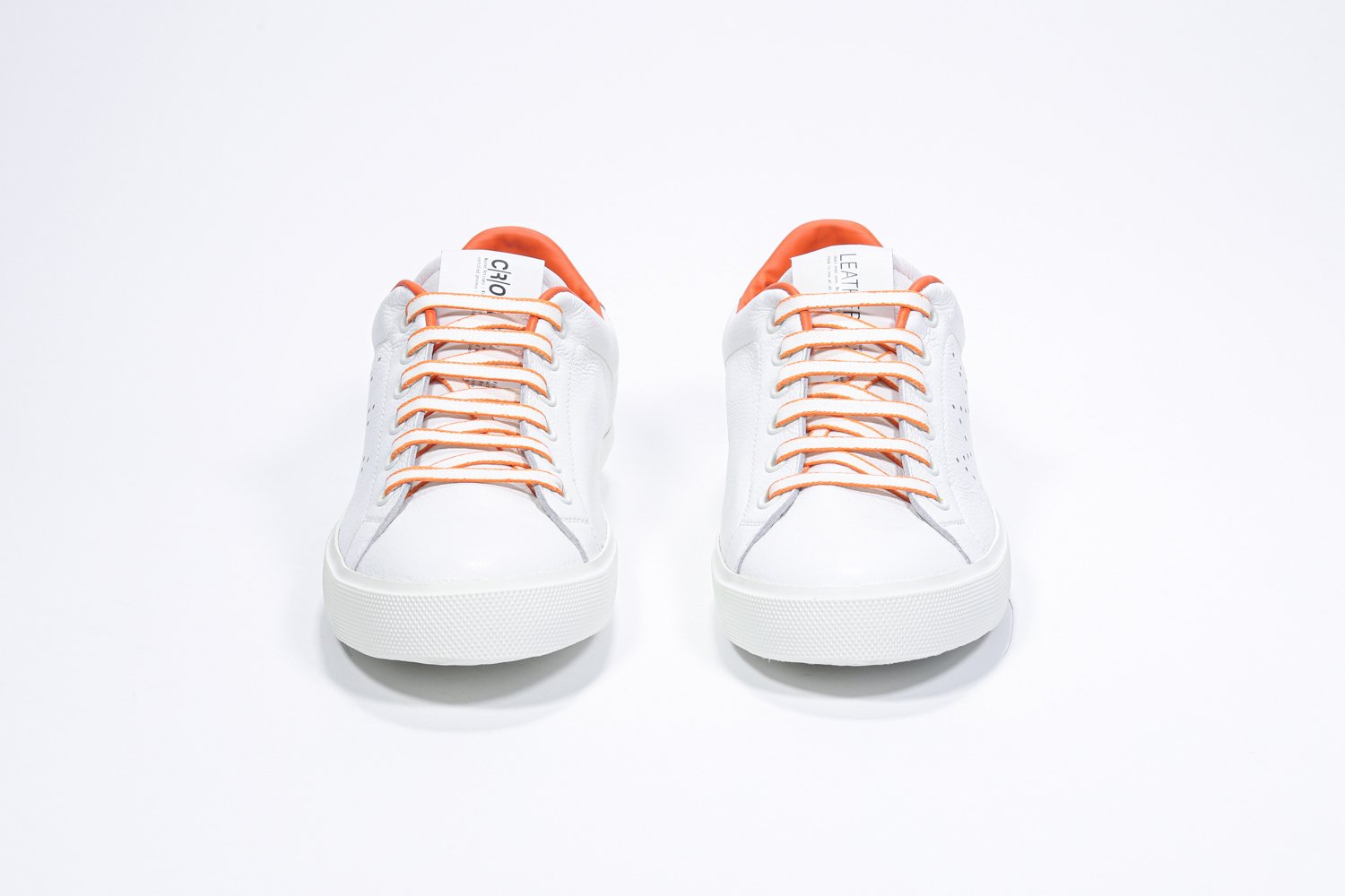 Vue de face de la chaussure blanche sneaker avec des détails orange et le logo perforé de la couronne sur la tige. Tige en cuir et semelle en caoutchouc blanc.