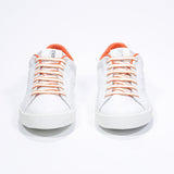 Front view of low top white sneaker with orange detailing and perforated crown logo on upper. Full leather upper and white rubber sole.