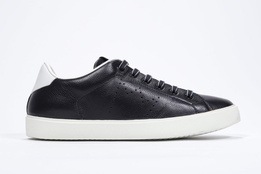 Side profile of low top black sneaker with white detailing and perforated crown logo on upper. Full leather upper and white rubber sole.