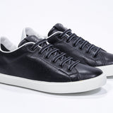 Three quarter front view of low top black sneaker with white detailing and perforated crown logo on upper. Full leather upper and white rubber sole.