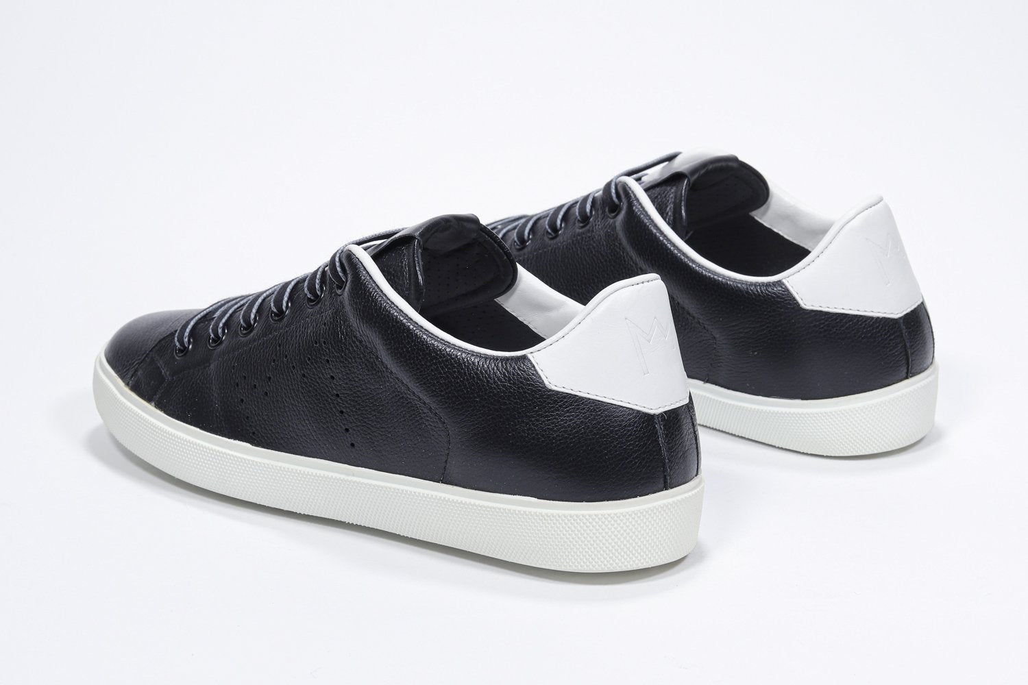 Three quarter back view of low top black sneaker with white detailing and perforated crown logo on upper. Full leather upper and white rubber sole.