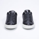 Front view of low top black sneaker with white detailing and perforated crown logo on upper. Full leather upper and white rubber sole.