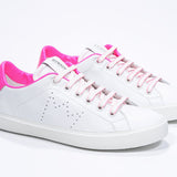 Three quarter front view of low top white sneaker with neon pink detailing and perforated crown logo on upper. Full leather upper and white rubber sole.