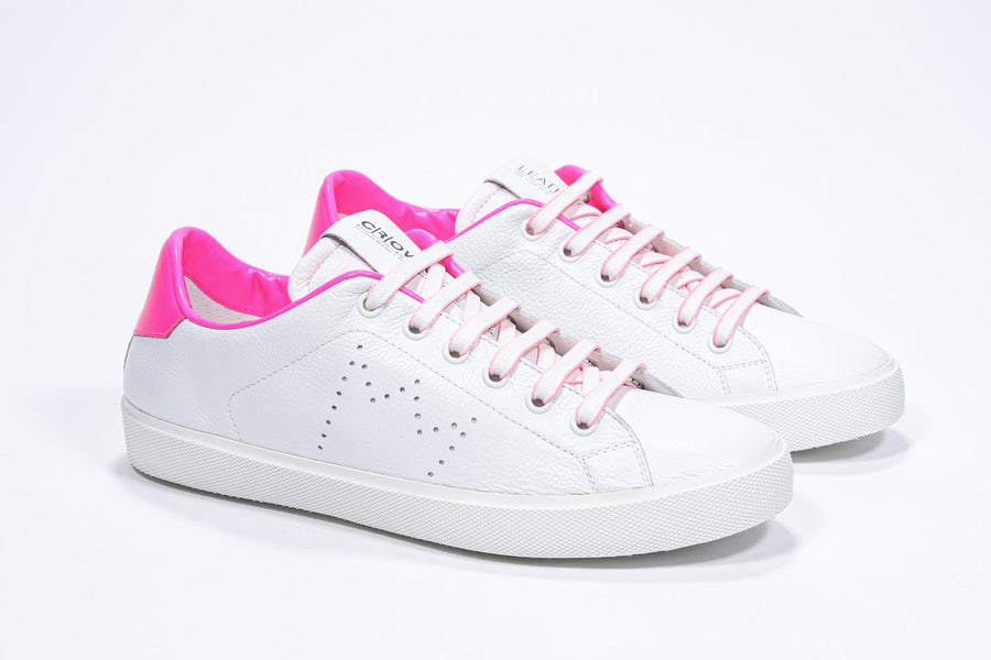 Three quarter front view of low top white sneaker with neon pink detailing and perforated crown logo on upper. Full leather upper and white rubber sole.