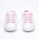 Front view of low top white sneaker with neon pink detailing and perforated crown logo on upper. Full leather upper and white rubber sole.