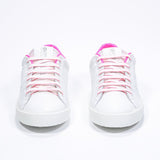 Vista frontale di BASSE  sneaker  bianco con dettagli rosa neon e logo della corona traforato sulla tomaia. Tomaia in pelle e suola in gomma bianca.
