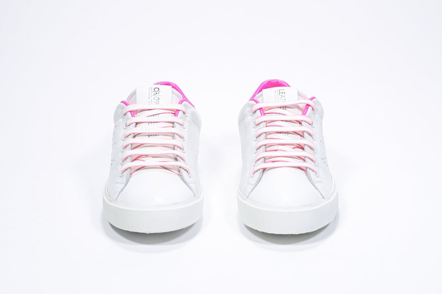 Front view of low top white sneaker with neon pink detailing and perforated crown logo on upper. Full leather upper and white rubber sole.