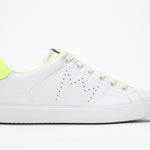 Side profile of low top white sneaker with neon yellow detailing and perforated crown logo on upper. Full leather upper and white rubber sole.