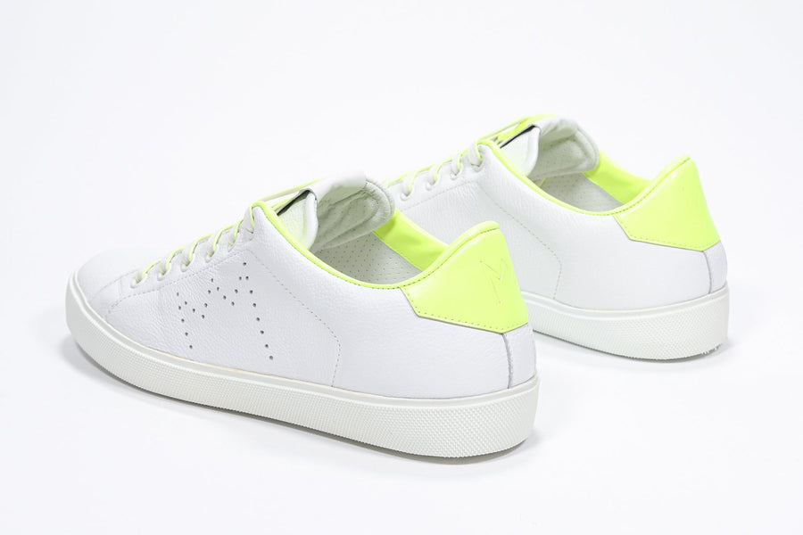 Three quarter back view of low top white sneaker with neon yellow detailing and perforated crown logo on upper. Full leather upper and white rubber sole.