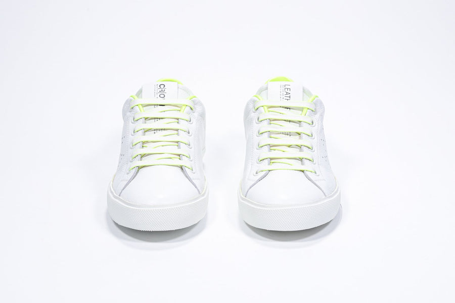 Front front view of low top white sneaker with neon yellow detailing and perforated crown logo on upper. Full leather upper and white rubber sole.