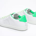 Three quarter back view of low top white sneaker with neon green detailing and perforated crown logo on upper. Full leather upper and white rubber sole.