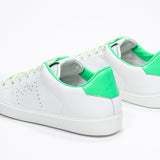 Vue de trois quarts arrière de la chaussure basse blanche sneaker avec des détails vert fluo et le logo perforé de la couronne sur la tige. Tige en cuir et semelle en caoutchouc blanc.