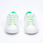 Vue avant de la chaussure blanche sneaker avec des détails vert fluo et le logo perforé de la couronne sur la tige. Tige en cuir et semelle en caoutchouc blanc.