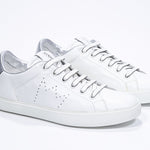 Three quarter front view of low top white sneaker with silver detailing and perforated crown logo on upper. Full leather upper and white rubber sole.