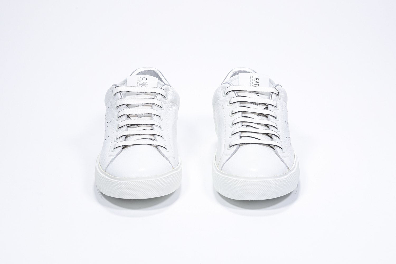 Vue de face de la chaussure blanche sneaker avec des détails argentés et le logo perforé de la couronne sur la tige. Tige en cuir et semelle en caoutchouc blanc.