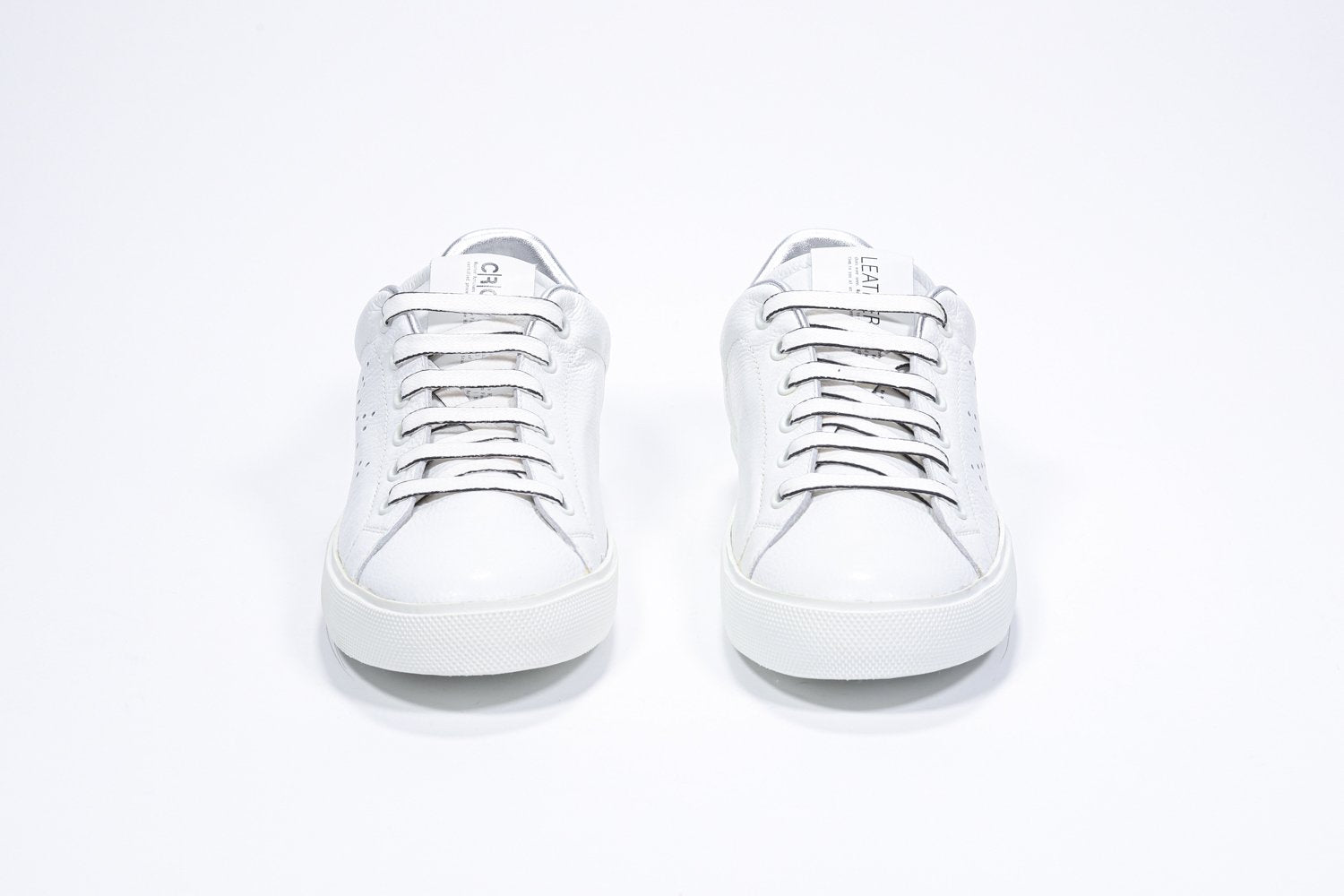 Front view of low top white sneaker with silver detailing and perforated crown logo on upper. Full leather upper and white rubber sole.