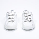 Front view of low top white sneaker with silver detailing and perforated crown logo on upper. Full leather upper and white rubber sole.