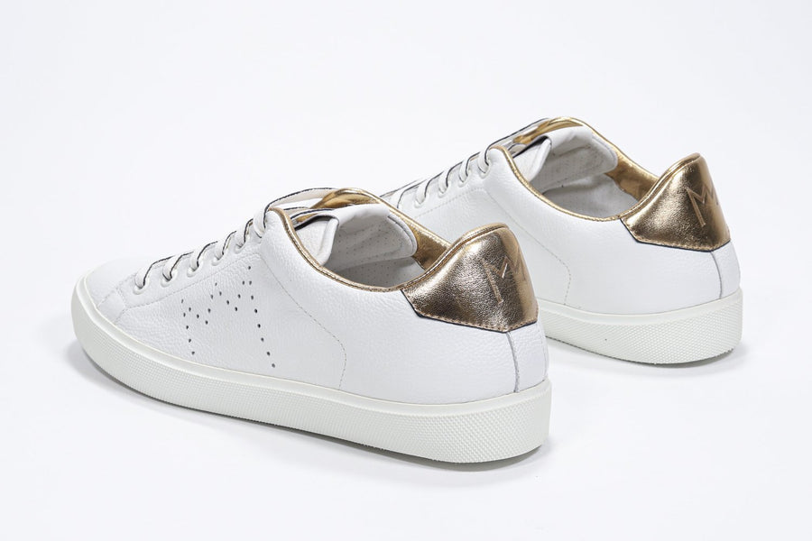 Three quarter back view of low top white sneaker with gold detailing and perforated crown logo on upper. Full leather upper and white rubber sole.
