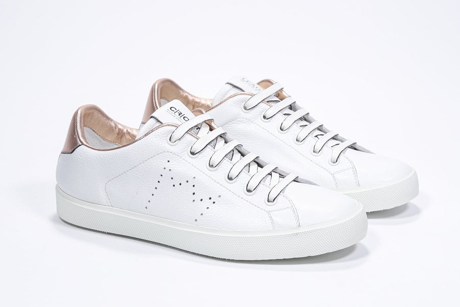 Three quarter front view of low top white sneaker with rose gold metallic detailing and perforated crown logo on upper. Full leather upper and white rubber sole.