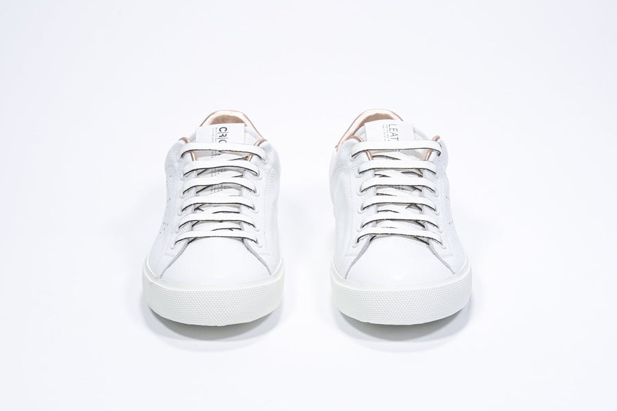 Front view of low top white sneaker with rose gold metallic detailing and perforated crown logo on upper. Full leather upper and white rubber sole.