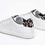 Three quarter back view of low top white sneaker with leopard print detailing and perforated crown logo on upper. Full leather upper and white rubber sole.