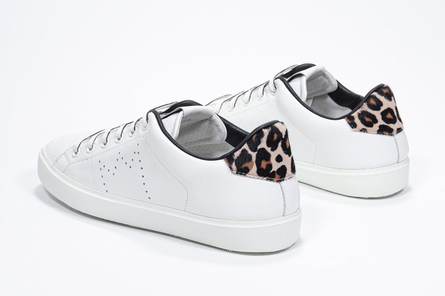 Three quarter back view of low top white sneaker with leopard print detailing and perforated crown logo on upper. Full leather upper and white rubber sole.