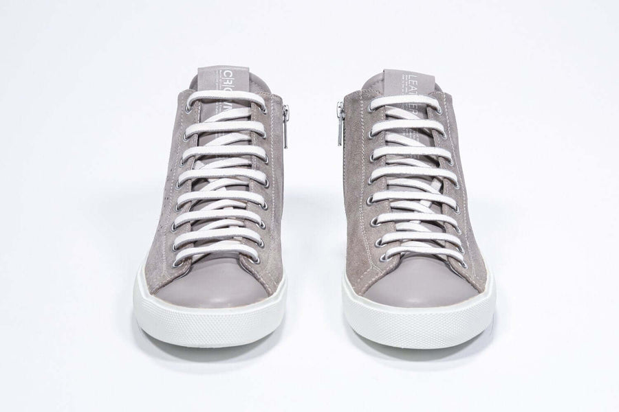 Front view of mid top beige sneaker with full suede upper with perforated crown logo, internal zip and white sole.
