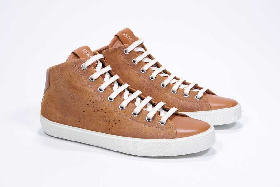 Three quarter front view of mid top rust sneaker with full suede upper with perforated crown logo, internal zip and white sole.