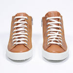 Front of mid top rust sneaker with full suede upper with perforated crown logo, internal zip and white sole.