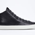 Side profile of mid top black sneaker with full leather upper with perforated crown logo, internal zip and white sole.