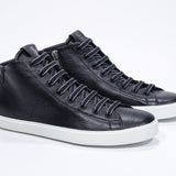 Three quarter front view of mid top black sneaker with full leather upper with perforated crown logo, internal zip and white sole.